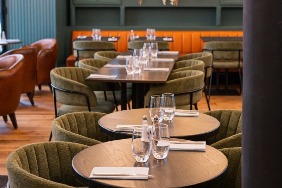 The dining room at Bistrot Jad, cognac leather armchairs and a flowered glass roof