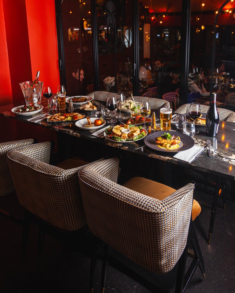A long laid table at Les Pipelettes du Boulevard, sharing dishes facing the boulevard