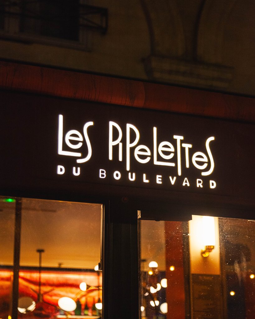 The neon sign of Les Pipelettes du Boulevard after dark